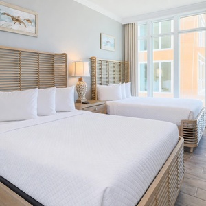 Unwind in this charming queen suite with two cozy beds and windows that showcase stunning beach views