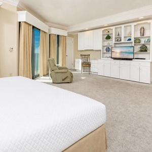 Elegant master bedroom on the beach with a king bed, cozy seating, and large windows offering beautiful views
