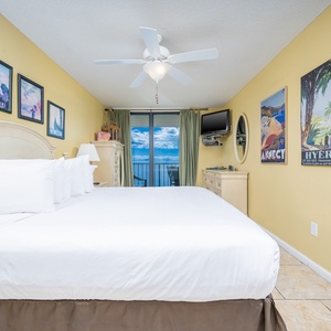 Inviting master bedroom with a king-size bed, coastal artwork, and a stunning view from the balcony