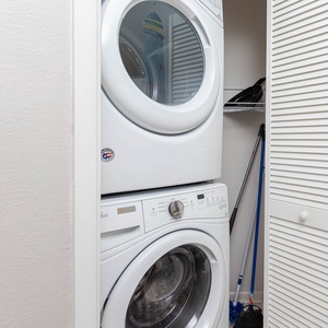 Stacked washer and dryer provide convenient laundry access, complemented by storage space for cleaning supplies