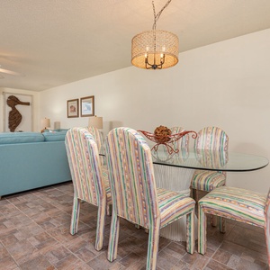 Dine comfortably at the glass table surrounded by colorful chairs, with the cozy living area nearby