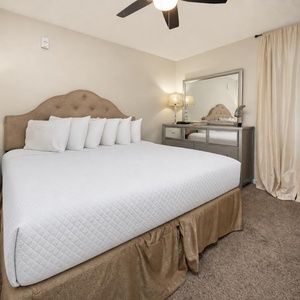 Elegant bedroom featuring a plush king bed, stylish nightstands, and a mounted TV, creating a serene retreat for relaxation