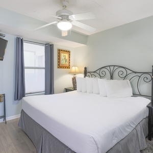 This inviting bedroom features a comfortable king bed, a flat-screen TV, and soft natural light from the window