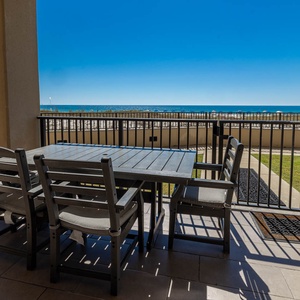 Enjoy meals or morning coffee at the outdoor dining table with a view of the sparkling beach in the distance