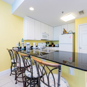 The bright kitchen features granite countertops, white cabinetry, and bar seating, perfect for casual dining and entertaining