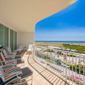 Enjoy vibrant striped seating on the balcony with sweeping views of lush landscapes and the sparkling coastline