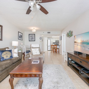 The living area features a plush sofa with queen sleeper, a large TV on a stylish stand, and a dining space