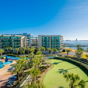 Gaze at the sparkling bay as you relax by the refreshing pool, surrounded by lush palm trees inviting tranquility