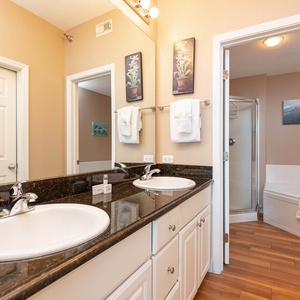 The master bathroom features dual sinks with a granite countertop, elegant decor, and jetted tub for a refreshing experience