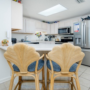 Gather around the stylish bar stools for casual meals in this inviting kitchen space, featuring stainless appliances