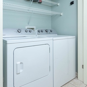 Washer and dryer set in a clean laundry area with a simple shelf above for added convenience and organization