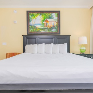 Relaxing guest bedroom featuring a king bed, colorful artwork, and a cozy lamp for a relaxing retreat