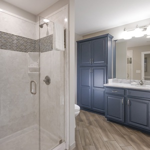 Enjoy a relaxing shower after a day at the beach in this guest bath with stylish cabinetry and spacious vanity