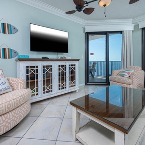 Unwind in the inviting living area, featuring a sofa with queen sleeper, large TV, and beachfront balcony access