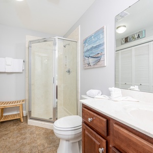 Additional bath featuring a walk-in shower, elegant countertops, laundry area with washer/dryer, and coastal artwork