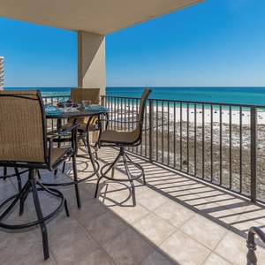 Outdoor patio set on the balcony offers a perfect spot to enjoy meals with a stunning view of the beach and turquoise gulf