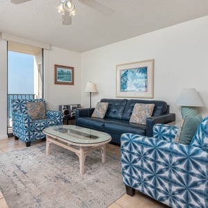 Relax in the inviting living area with comfortable seating, a glass coffee table, and beautiful balcony views