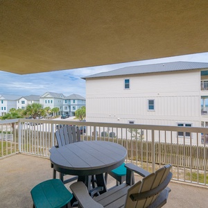 Relax on the private balcony with a cozy table and chairs, enjoying the serene coastal view and nearby palm trees