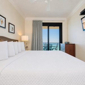 Serene master bedroom with a plush king bed, a TV, and a balcony offering views of the tranquil waters