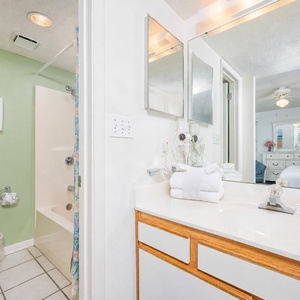 Master bathroom featuring a white sink, green accent wall, and a tub/shower combo with a floral curtain for a refreshing feel