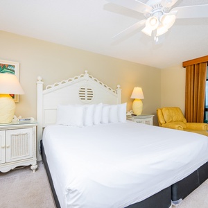 The master suite features a king bed, cozy armchair, and sliding doors leading to a balcony with gulf views