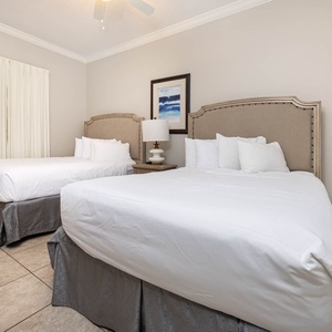 Inviting guest bedroom with two queen beds, soft linens, and natural light from the window