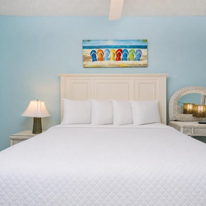Serene blue walls of this inviting guest bedroom with a plush queen bed and stylish nightstand create a coastal vibe