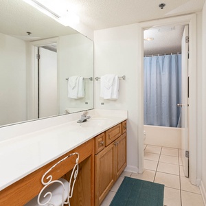 Master bathroom featuring a spacious vanity with ample counter space, a tub/shower combo, and a calming blue shower curtain