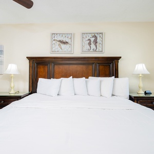 Master bedroom featuring a large king bed with plush pillows and charming coastal artwork on the walls