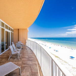 Spacious balcony with comfortable seating, featuring stunning views of the beach and inviting blue waters