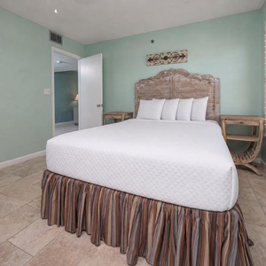 This guest bedroom features a stylish wooden headboard, queen with soft bedding, and a charming side table