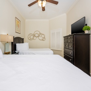 This guest bedroom features two comfortable queen beds, a flat-screen TV, and stylish decor, perfect for a relaxing stay