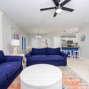 Relax on the deep blue sofas surrounded by vibrant decor and a bright, open layout leading to the dining area