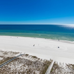 Expansive view of the pristine white sand beach and clear turquoise waters under a bright blue sky, perfect for relaxation