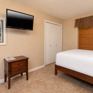 Brightly decorated guest room features two double beds, a mounted TV, and a charming artwork, creating a relaxing retreat