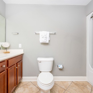 This bathroom features a sleek vanity with dark wood cabinetry, fresh towels, and a clean shower area for a refreshing stay