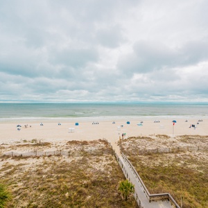 This view showcases a serene beachfront, inviting guests to relax on the sand under colorful umbrellas