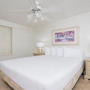 Guest bedroom featuring a queen bed with crisp white linens, decorative artwork, and warm bedside lamps