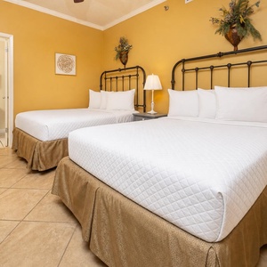 Bright yellow walls complement two double beds, creating a cheerful and inviting atmosphere in this guest room