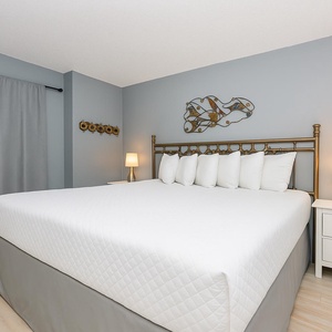 Retreat to this elegant king suite with fluffy pillows, soft gray walls, and a stylish lamp for a relaxing stay