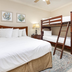 Rest in this cozy guest bedroom featuring a double bed, twin bunk beds, and charming coastal decor for a relaxed stay