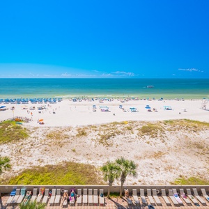 Bask in the sun on the pristine beach, dotted with colorful umbrellas and lounge chairs, under a bright blue sky