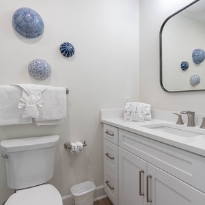 This bathroom features elegant blue decor, a stylish mirror, and a clean, white vanity with ample storage