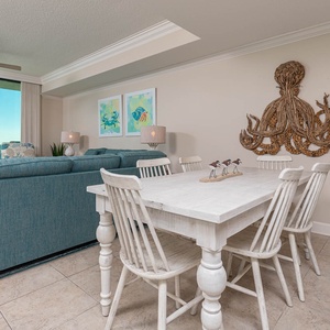 Gather around the dining table, surrounded by coastal decor and inviting seating, perfect for meals and conversation