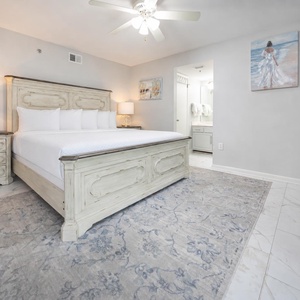 Stylish master bedroom featuring a king bed, elegant furnishings, and an ensuite bathroom visible in the background