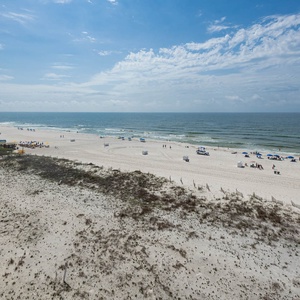 Gaze at the inviting shoreline, where guests can relax under umbrellas and enjoy the gentle waves lapping at the shore