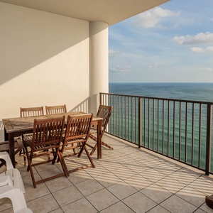 This spacious balcony features a wooden dining set, perfect for enjoying meals with a beach view
