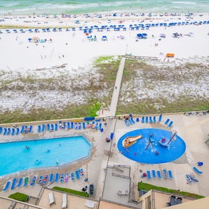 A vibrant pool area features the pirate ship splash park, leading to a pristine beach with white sand