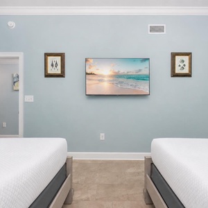 Tranquil guest bedroom with two queen beds, soft linens, and a wall-mounted TV