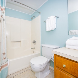 The bathroom features a clean, bright design with a shower/tub combo and fresh towels for a refreshing experience